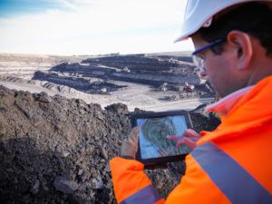 Ecologist using digital tablet surveying surface coal mine site, elevated view --- Image by © Monty Rakusen/cultura/Corbis