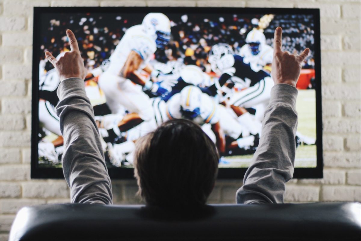 The man watches on sports the channel on TV the American football