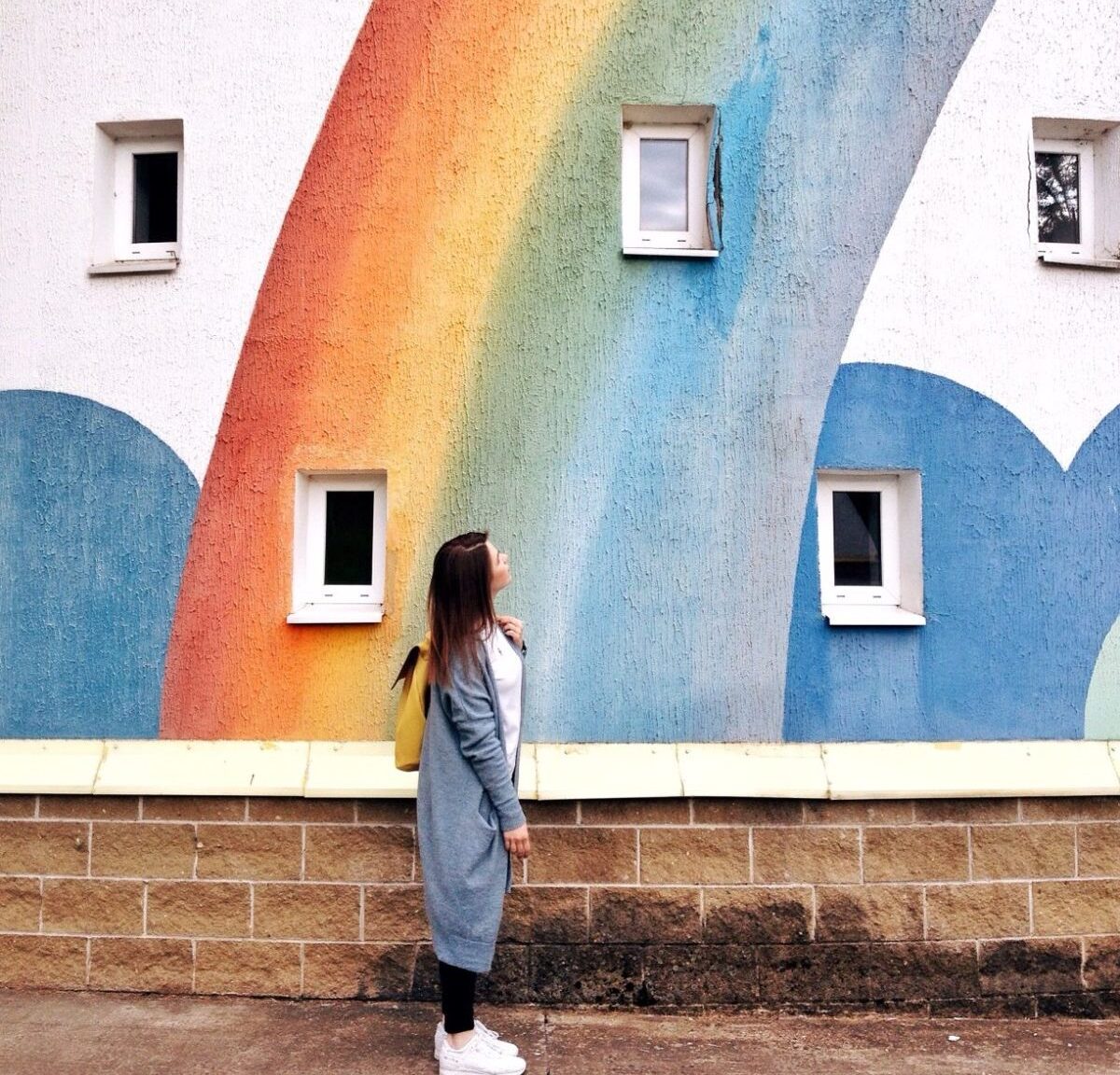 womwoman looking up at rainbow wall