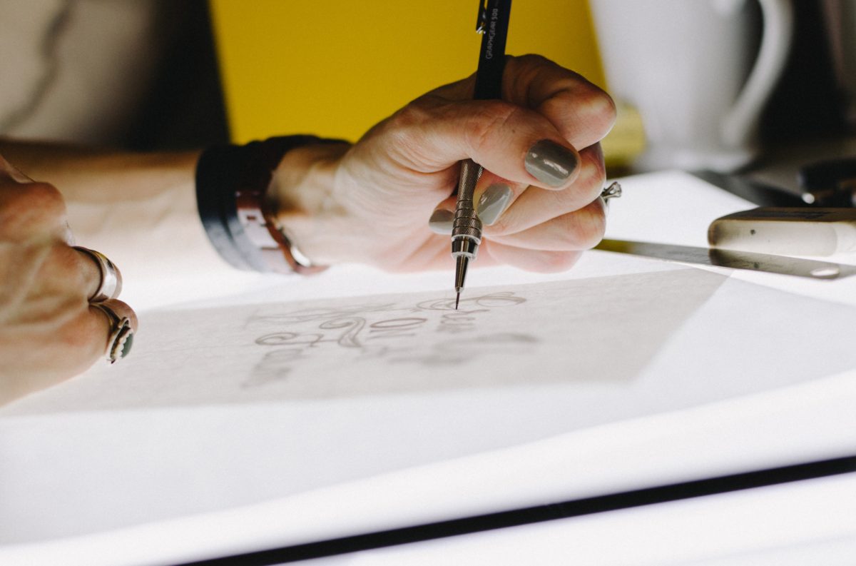 Woman drawing a design on paper with ink pen