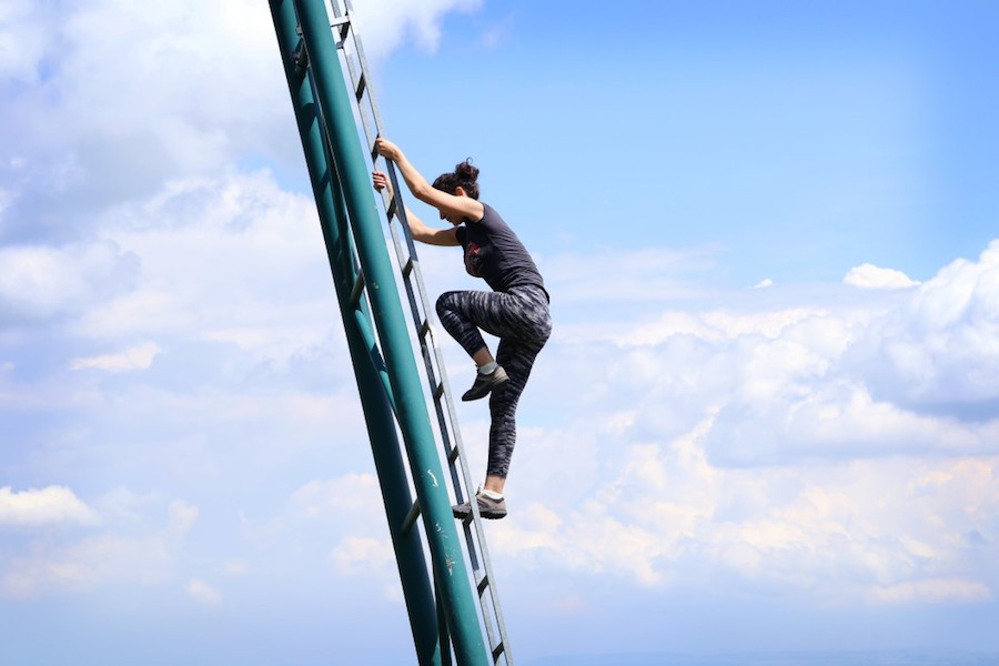 wWoman climbing metal ladder